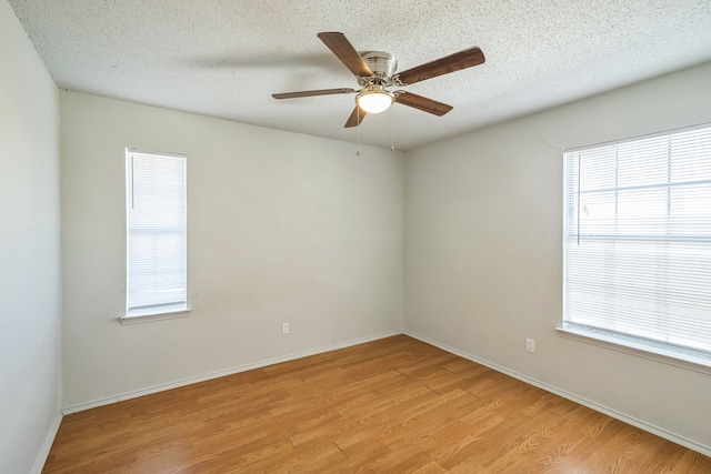 unfurnished room featuring ceiling fan, a healthy amount of sunlight, a textured ceiling, and light wood-type flooring