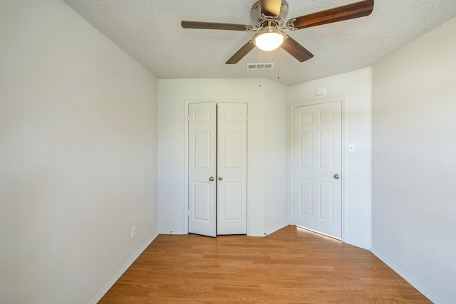 unfurnished bedroom with a closet, a textured ceiling, light wood-type flooring, and ceiling fan