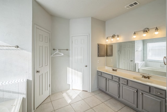 bathroom featuring vanity, tile patterned flooring, a textured ceiling, and a bathing tub