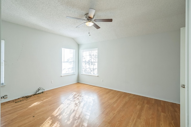 empty room with ceiling fan, a textured ceiling, vaulted ceiling, and light wood-type flooring