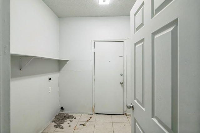 clothes washing area with light tile patterned flooring, a textured ceiling, and hookup for an electric dryer