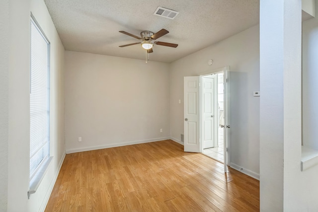 empty room featuring a textured ceiling, light hardwood / wood-style floors, and ceiling fan