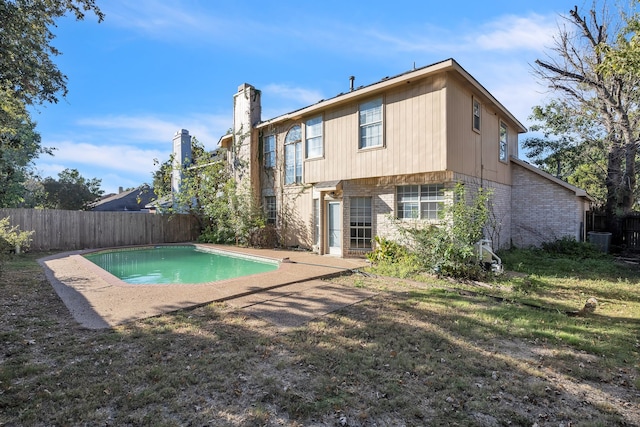 back of property featuring a patio area, a lawn, and a fenced in pool