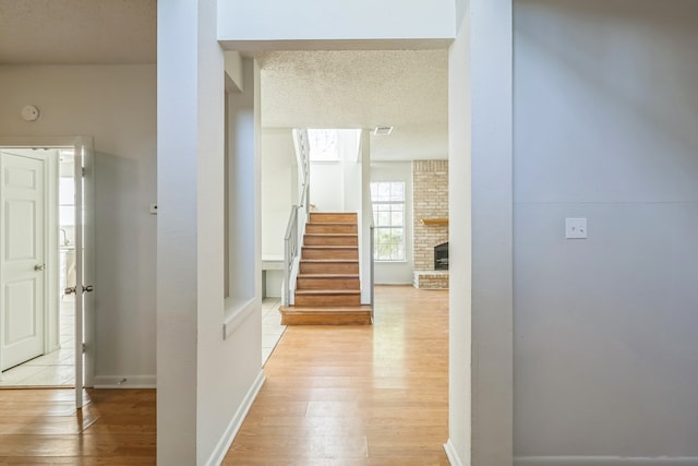 hall featuring a textured ceiling and light hardwood / wood-style floors