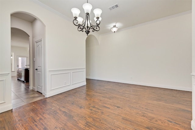 empty room featuring a notable chandelier, dark wood-type flooring, and crown molding