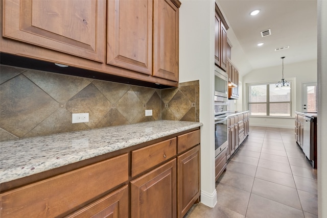 kitchen featuring pendant lighting, light stone counters, light tile patterned flooring, decorative backsplash, and appliances with stainless steel finishes