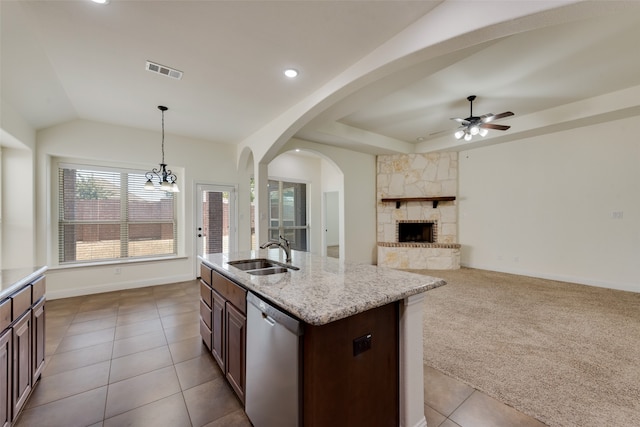 kitchen with dishwasher, sink, ceiling fan with notable chandelier, light colored carpet, and a stone fireplace