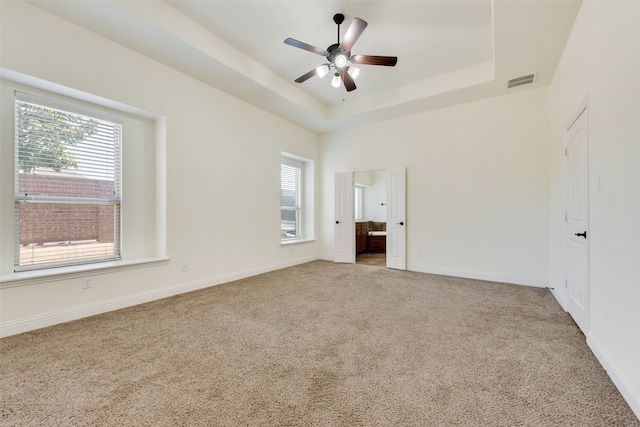 carpeted empty room featuring a tray ceiling and ceiling fan