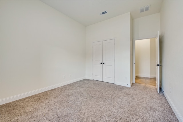 unfurnished bedroom with a closet and light colored carpet