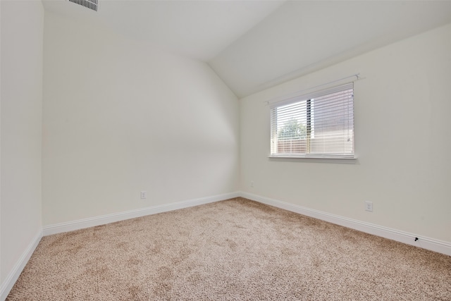 carpeted spare room featuring lofted ceiling