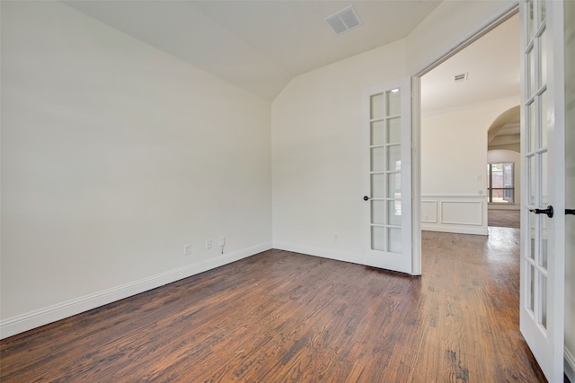 empty room featuring lofted ceiling, dark hardwood / wood-style floors, and french doors