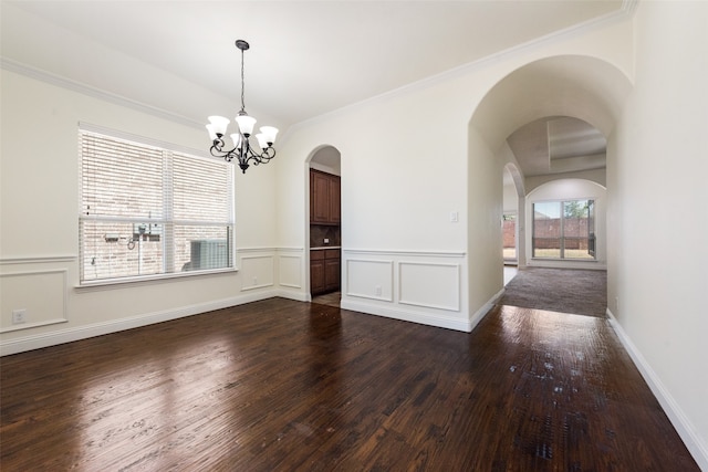 unfurnished room featuring an inviting chandelier, dark hardwood / wood-style floors, and ornamental molding