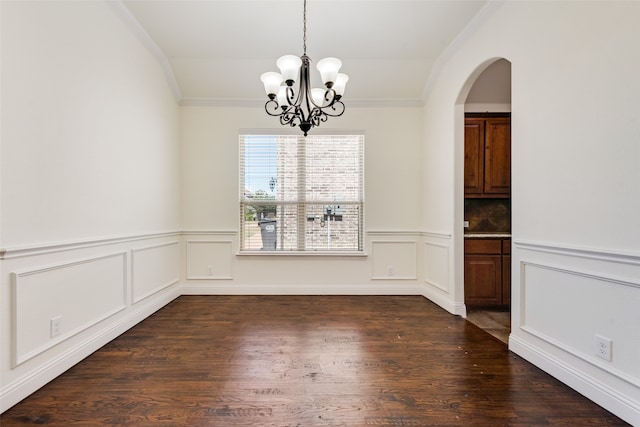 unfurnished dining area featuring ornamental molding, an inviting chandelier, and dark wood-type flooring