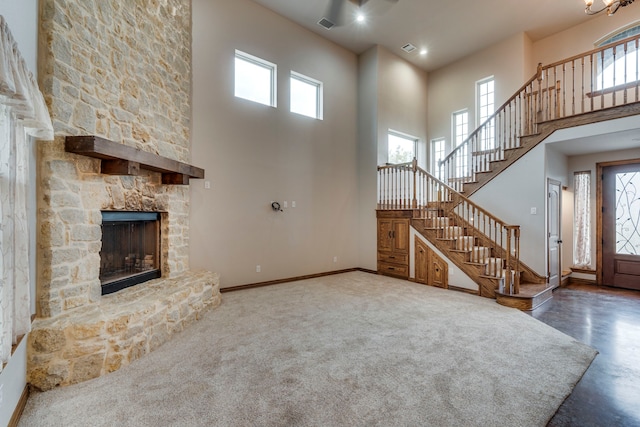 unfurnished living room featuring a towering ceiling, carpet, and a stone fireplace