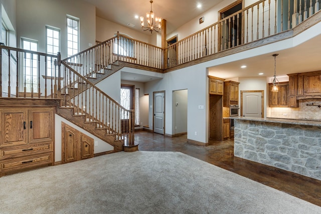 unfurnished living room featuring an inviting chandelier, a healthy amount of sunlight, a towering ceiling, and dark hardwood / wood-style floors