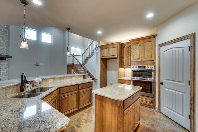 kitchen with light stone countertops, a center island, decorative light fixtures, double oven, and sink