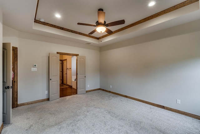 carpeted empty room featuring a raised ceiling, ornamental molding, and ceiling fan