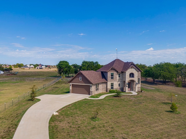 view of front of house featuring a garage, a front lawn, and a rural view