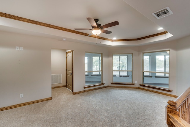 carpeted empty room with ceiling fan, a raised ceiling, and crown molding