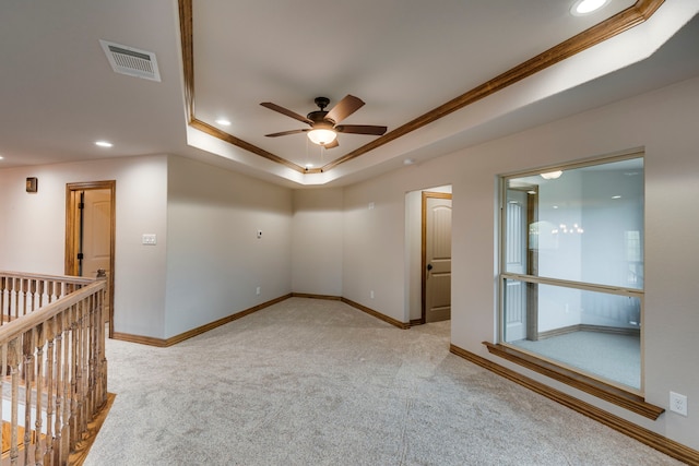 carpeted spare room featuring ceiling fan, a raised ceiling, and crown molding