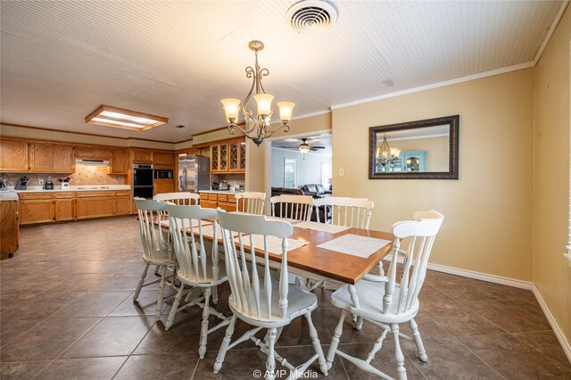 dining space with ceiling fan with notable chandelier, dark tile patterned floors, and crown molding