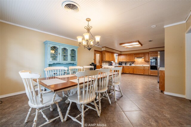 dining area featuring an inviting chandelier, crown molding, and dark tile patterned floors