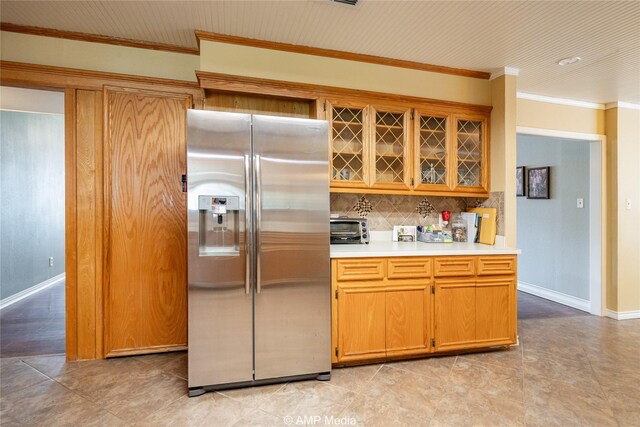 kitchen featuring ornamental molding, stainless steel refrigerator with ice dispenser, light tile patterned floors, and backsplash