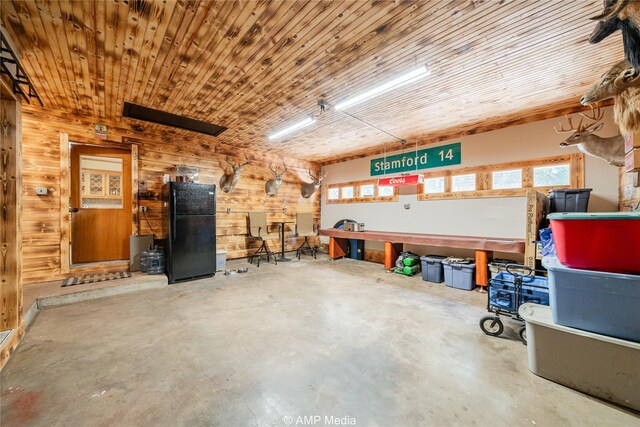 garage featuring wooden ceiling, wooden walls, and black refrigerator