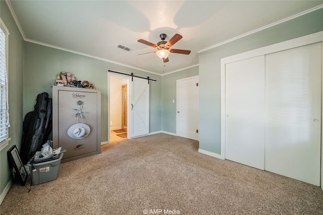 unfurnished bedroom featuring a barn door, ornamental molding, light carpet, and ceiling fan