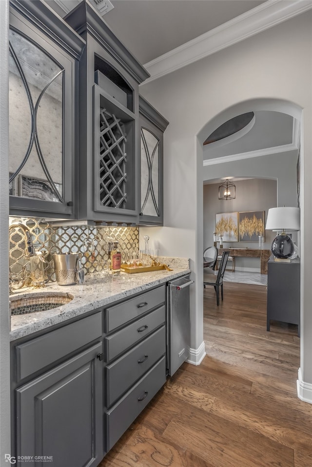 bar with gray cabinets, dark hardwood / wood-style flooring, backsplash, crown molding, and light stone countertops