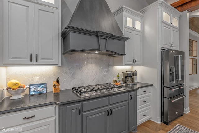 kitchen with custom exhaust hood, appliances with stainless steel finishes, decorative backsplash, and white cabinetry