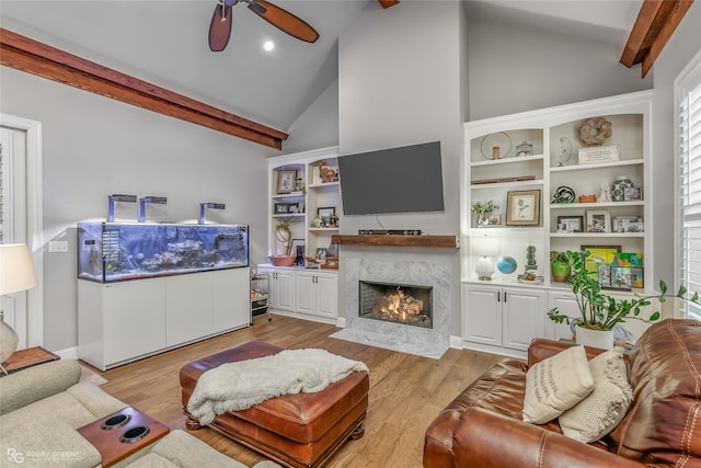 living room with vaulted ceiling with beams, ceiling fan, light hardwood / wood-style floors, and a fireplace