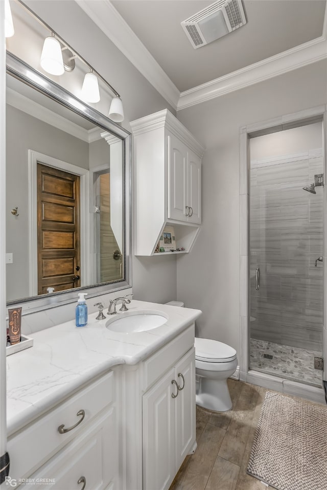 bathroom with crown molding, vanity, toilet, and a shower with shower door