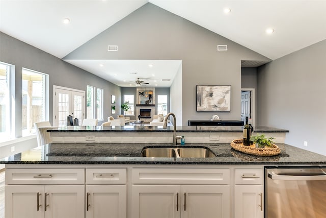 kitchen with dishwasher, sink, white cabinets, vaulted ceiling, and ceiling fan