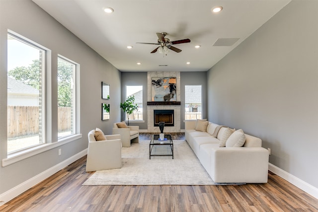 living room with ceiling fan, hardwood / wood-style floors, and a tile fireplace