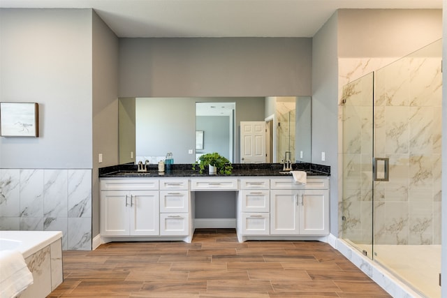 bathroom with wood-type flooring, vanity, plus walk in shower, and tile walls