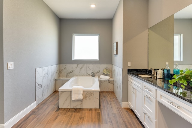 bathroom featuring tiled tub, vanity, and hardwood / wood-style floors