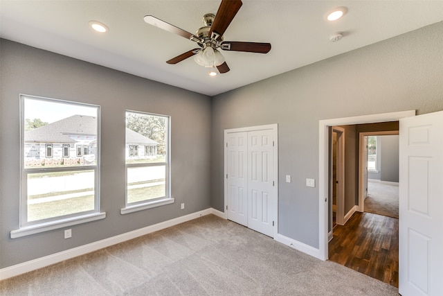 unfurnished bedroom featuring multiple windows, dark carpet, and ceiling fan