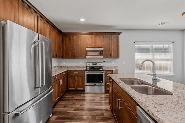 kitchen with light stone counters, dark wood-type flooring, sink, and stainless steel appliances