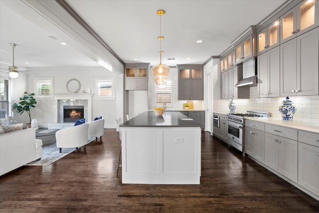 kitchen featuring high end stove, a high end fireplace, exhaust hood, ceiling fan, and dark hardwood / wood-style floors