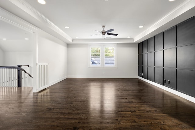 spare room featuring ornamental molding, a tray ceiling, ceiling fan, and dark wood-type flooring