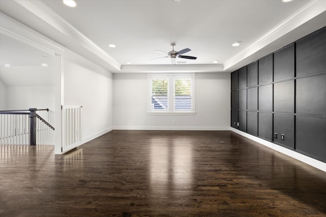 spare room with a raised ceiling, ceiling fan, dark wood-type flooring, and crown molding