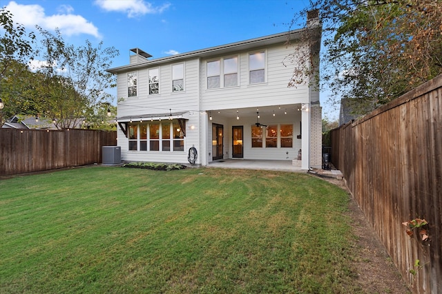 rear view of house with a lawn, central AC, and a patio area