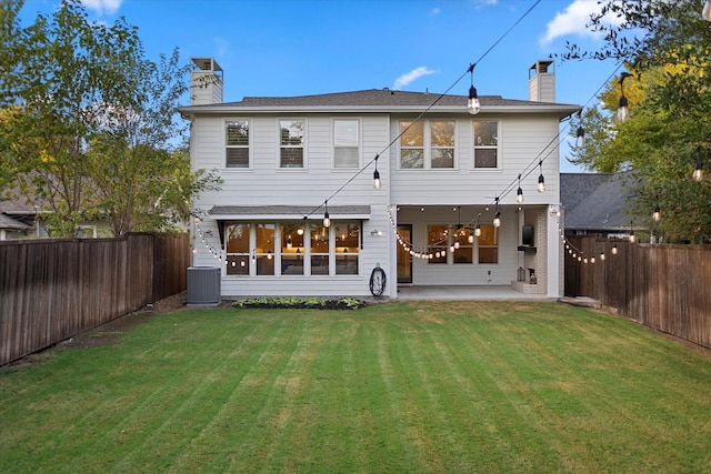 rear view of property with a yard, central AC, and a patio area