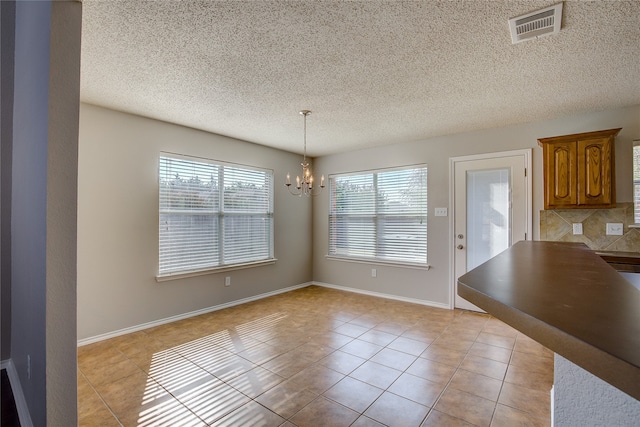 unfurnished dining area featuring a notable chandelier, light tile patterned floors, and a wealth of natural light