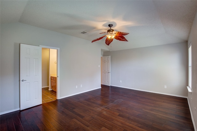 empty room with a textured ceiling, lofted ceiling, dark hardwood / wood-style floors, and ceiling fan