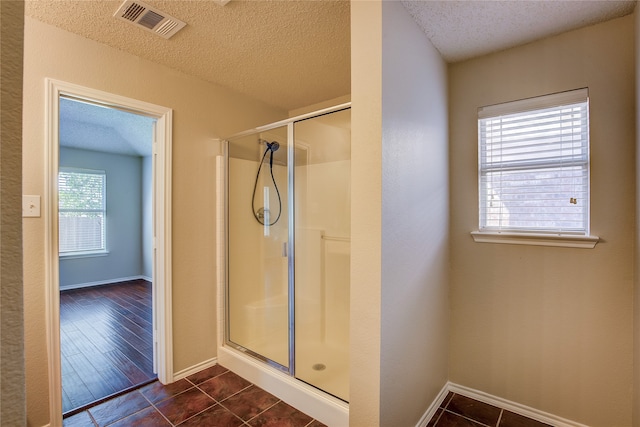 bathroom with wood-type flooring, a textured ceiling, and an enclosed shower