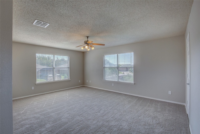 carpeted spare room with ceiling fan, a textured ceiling, and a healthy amount of sunlight