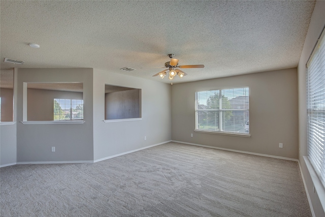 spare room featuring ceiling fan, a textured ceiling, light carpet, and a wealth of natural light