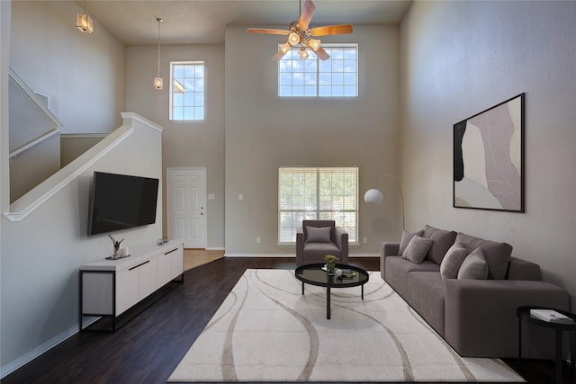 living room featuring ceiling fan, a textured ceiling, dark wood-type flooring, and a high ceiling